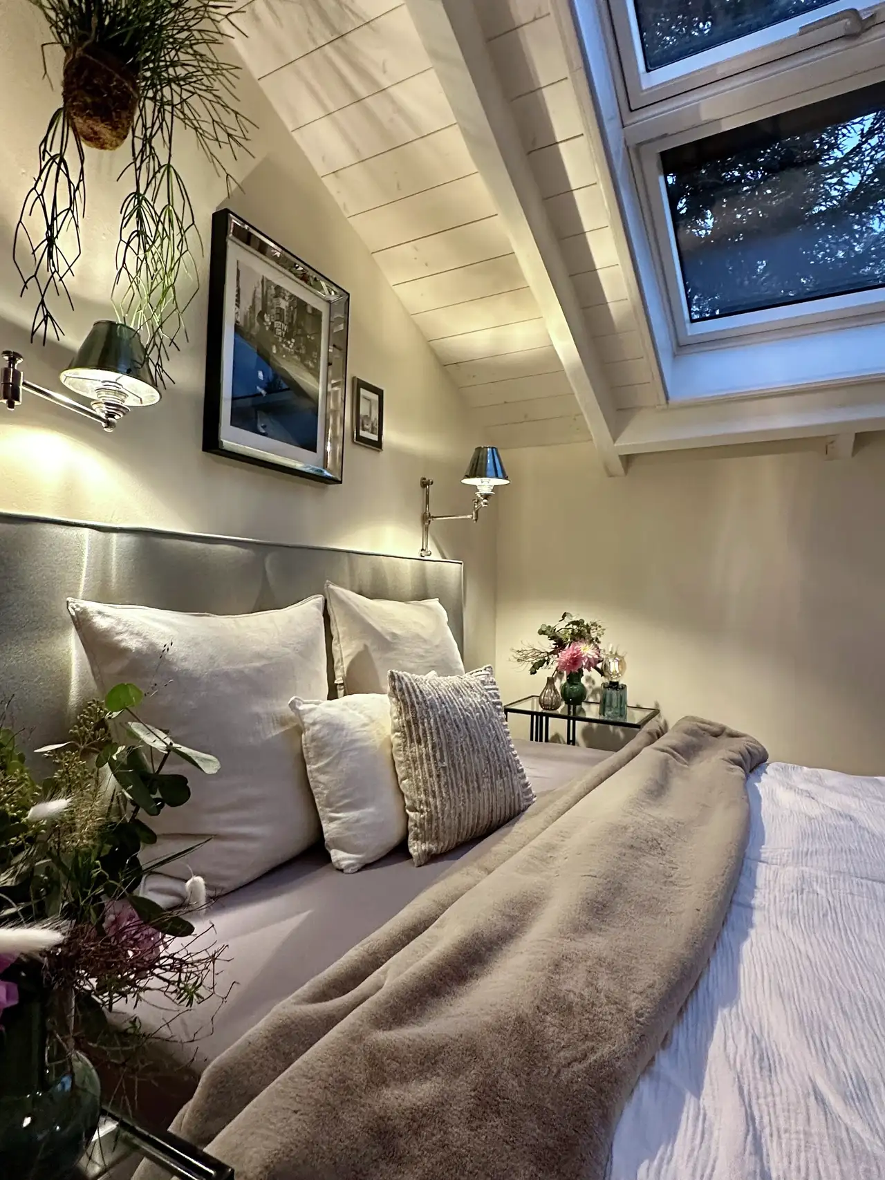 Attic bedroom with sloped ceiling and VELUX roof windows, modern decor. 