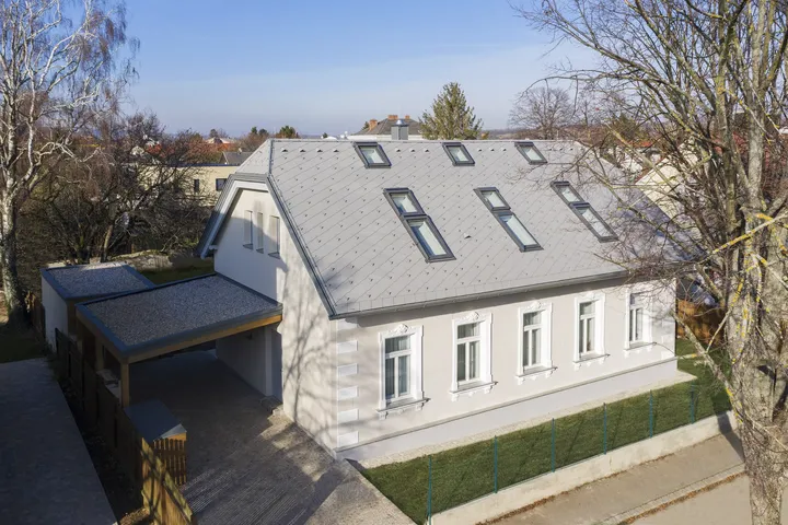 Renoviertes weißes Einfamilienhaus mit VELUX Dachflächenfenstern und angebautem Carport.