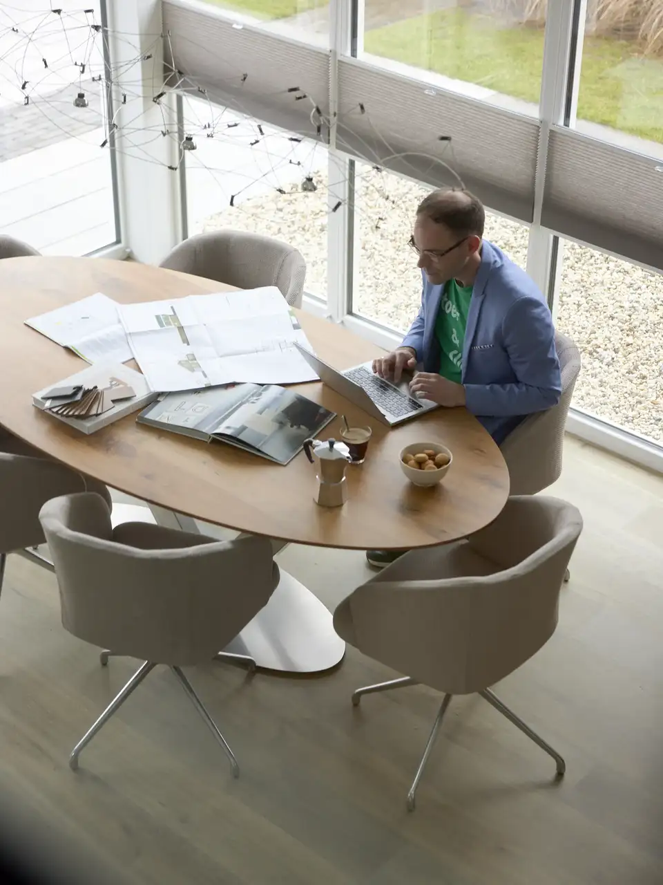 Vergaderruimte met grote ramen, houten tafel en ontwerpmaterialen