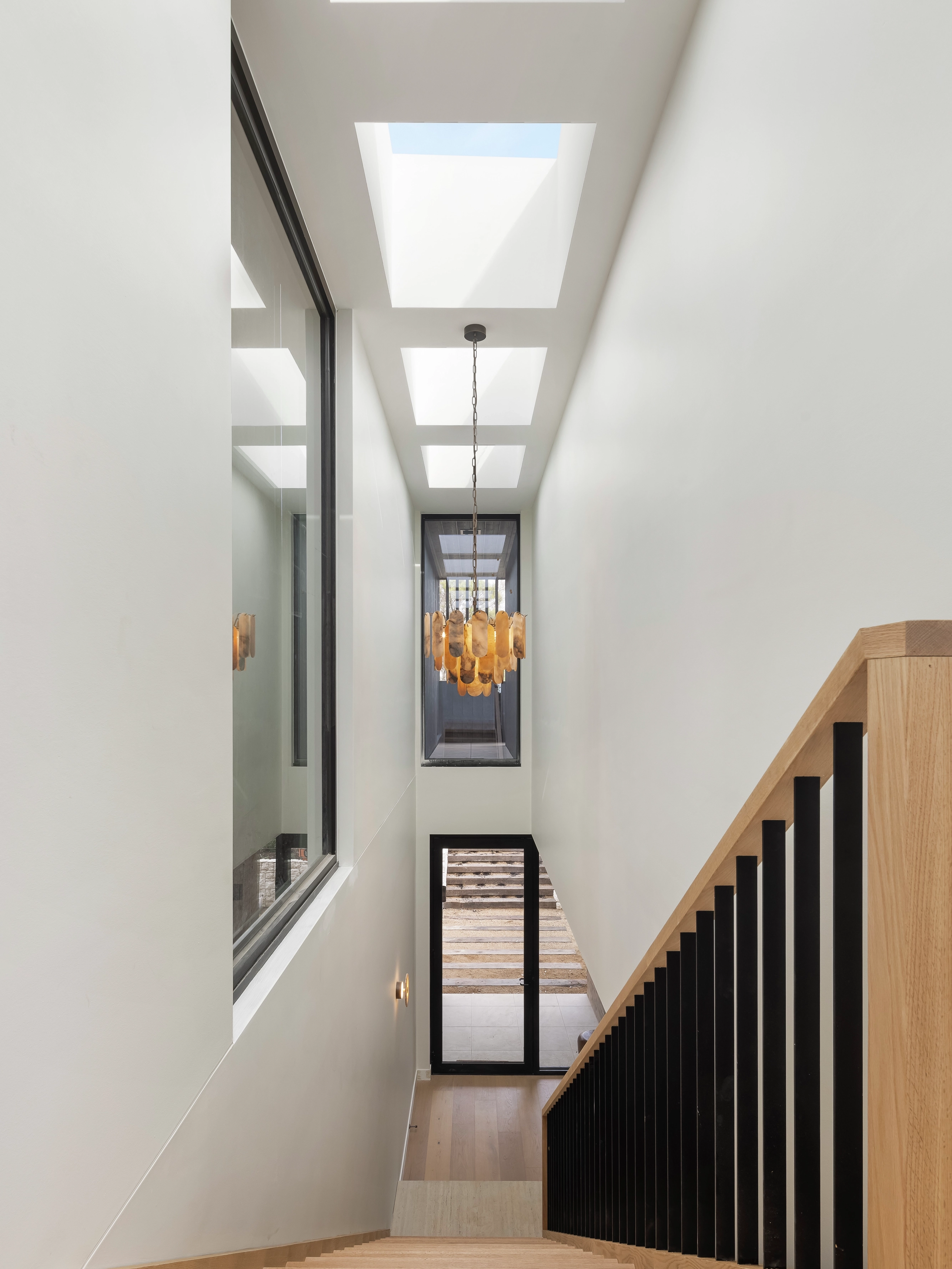 Modern staircase lit by three VELUX flat roof windows above and a warm pendant light.