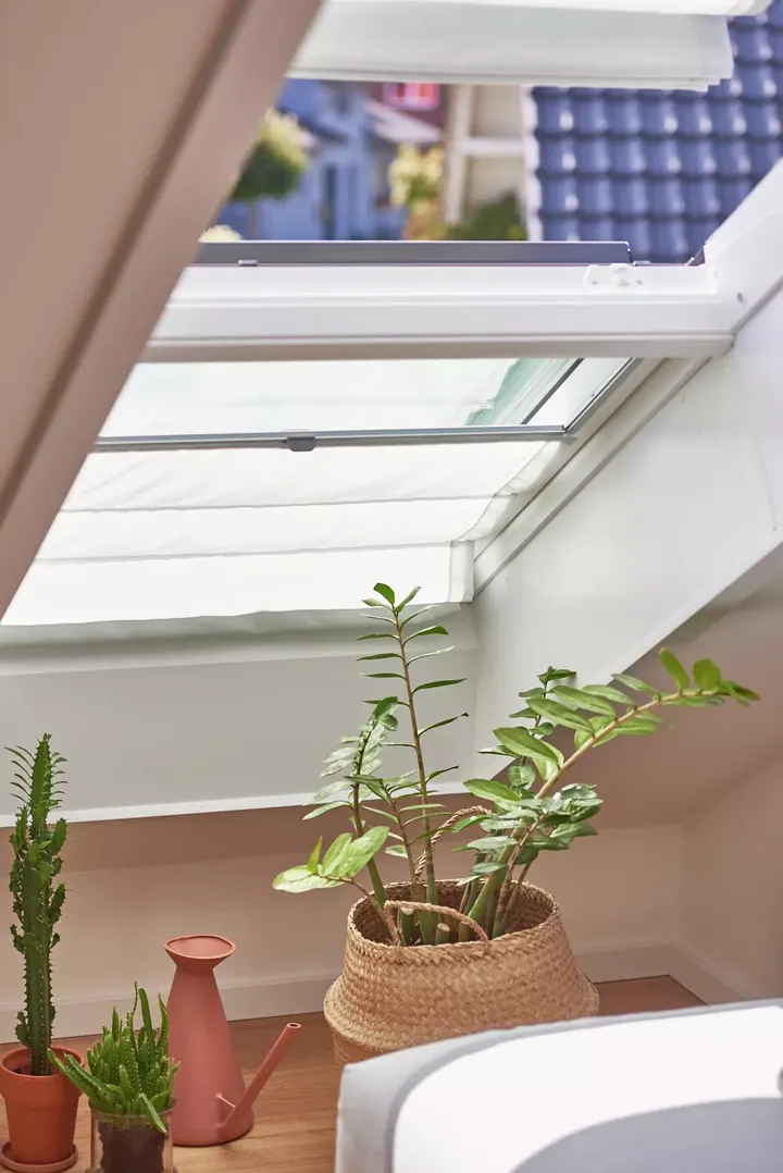 Gemütliches Dachboden-Zimmer mit VELUX Dachflächenfenster, Pflanzen und moderner Einrichtung.