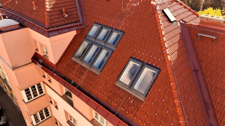 Luftaufnahme von Terrakotta-geziegeltem Dach mit VELUX Dachflächenfenstern auf städtischem Gebäude.