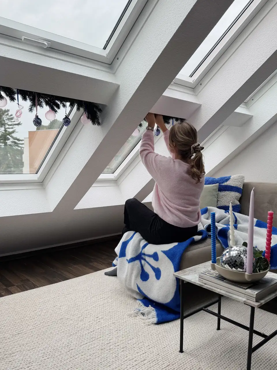 Stanza in mansarda decorata per Natale con candele rosse accese al tramonto e decorazioni sulle finestre per tetti VELUX