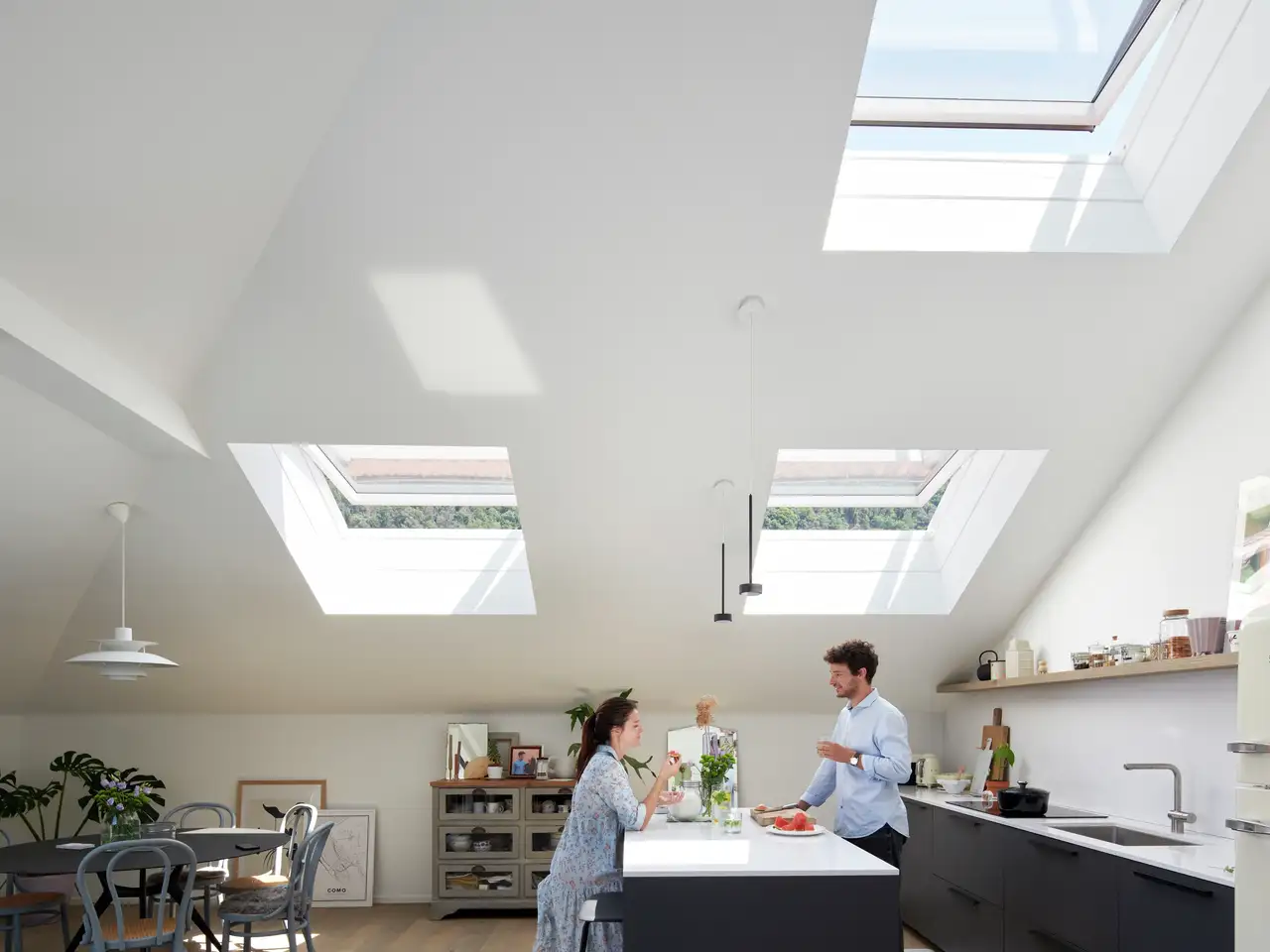 VELUX çatı pencereli, açık plan bir yemek alanında öğle yemeği yiyen bir çift.