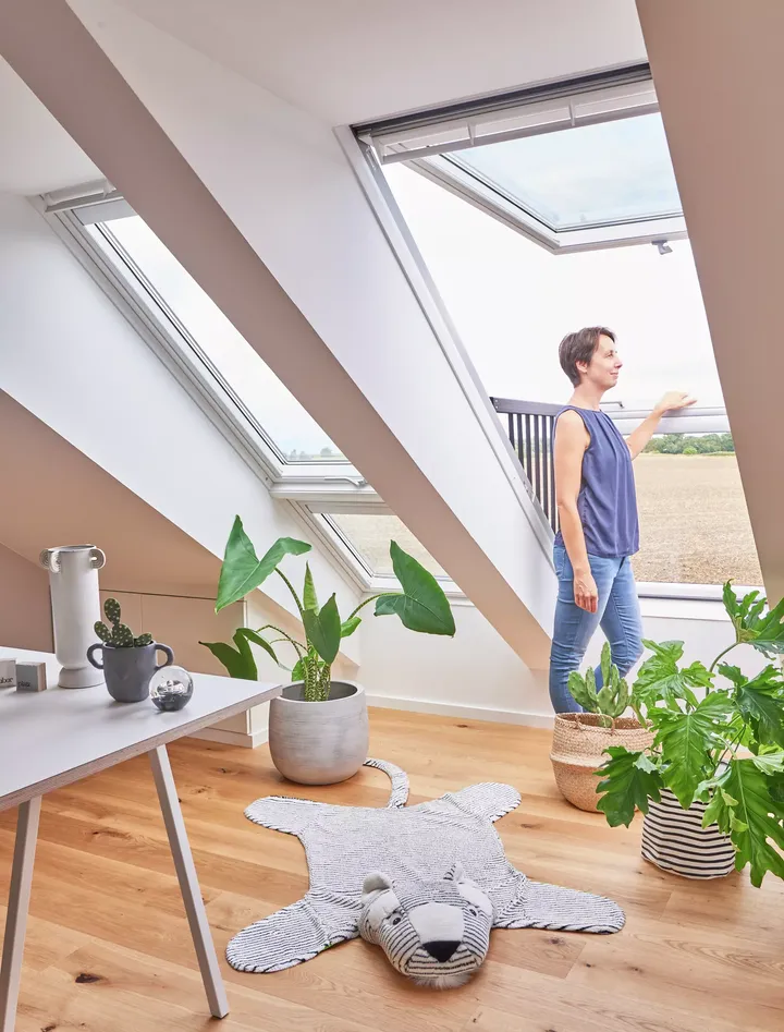 Dachboden-Heimbüro mit VELUX-Fenster, Pflanzen, Schreibtisch und Tigerteppich.