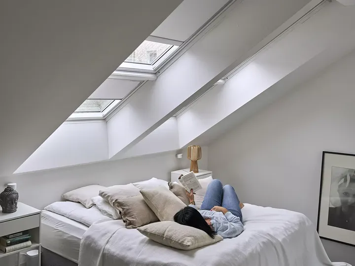 Gemütliches Dachboden-Schlafzimmer mit natürlichem Licht von VELUX Dachflächenfenstern und minimalistischer Dekoration.