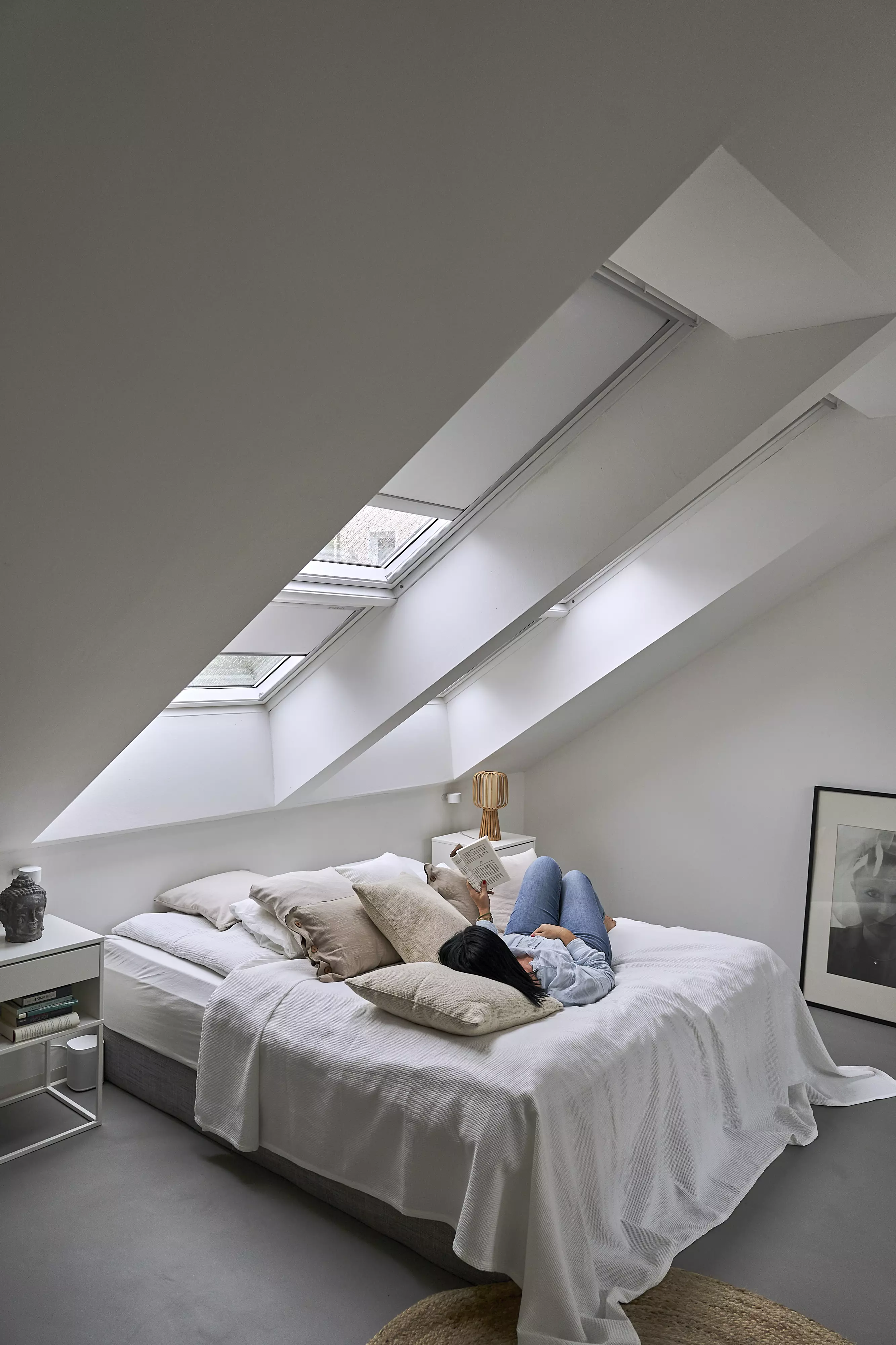 Gemütliches Dachboden-Schlafzimmer mit Bett, kuscheligen Kissen und natürlichem Licht von VELUX Dachflächenfenstern.