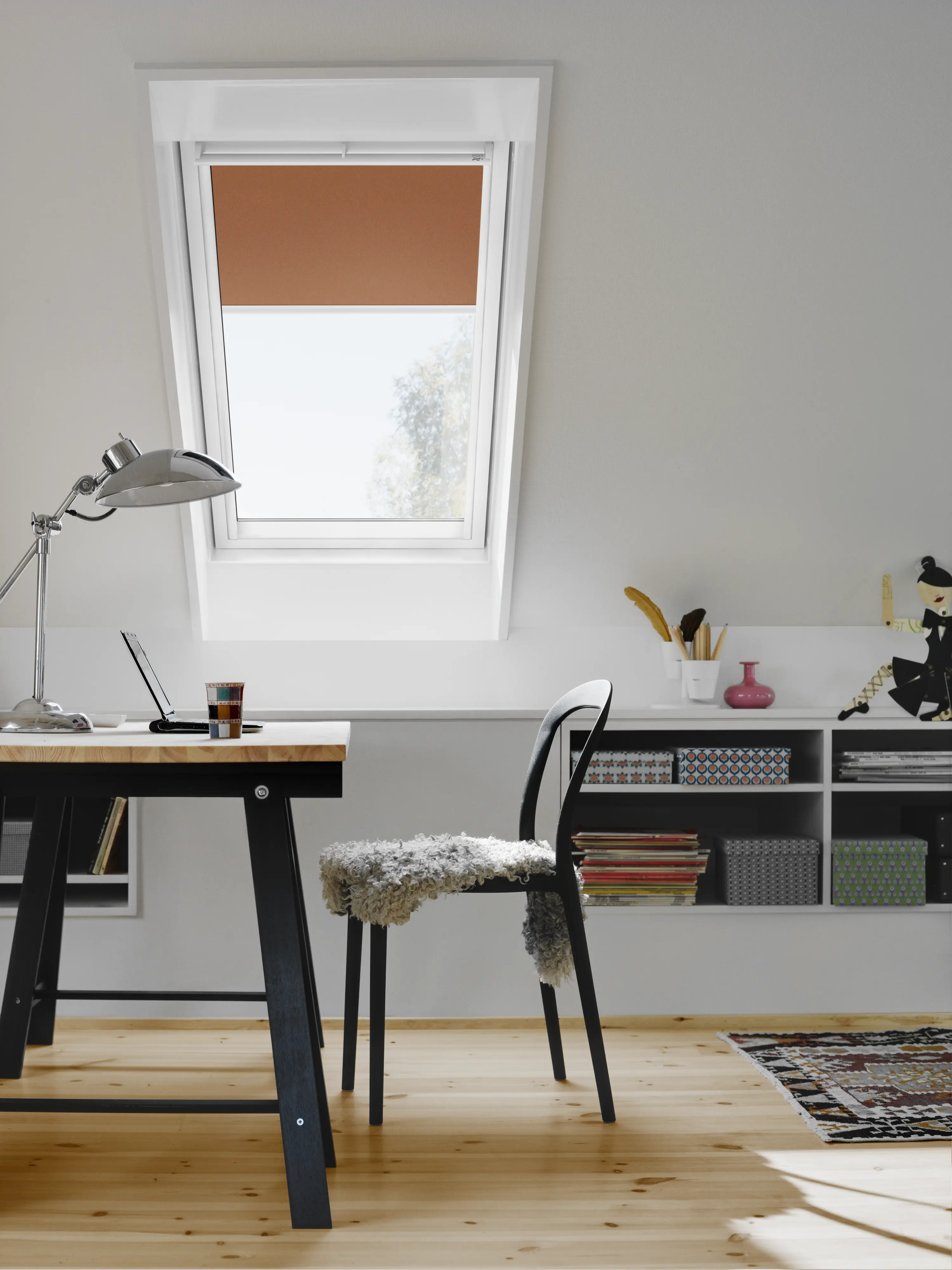 Bureau sous combles avec plafond incliné, fenêtre de toit, bureau et chaise.