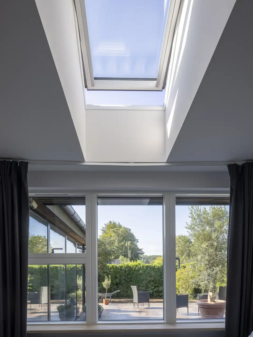 Bedroom with VELUX roof window and garden view.