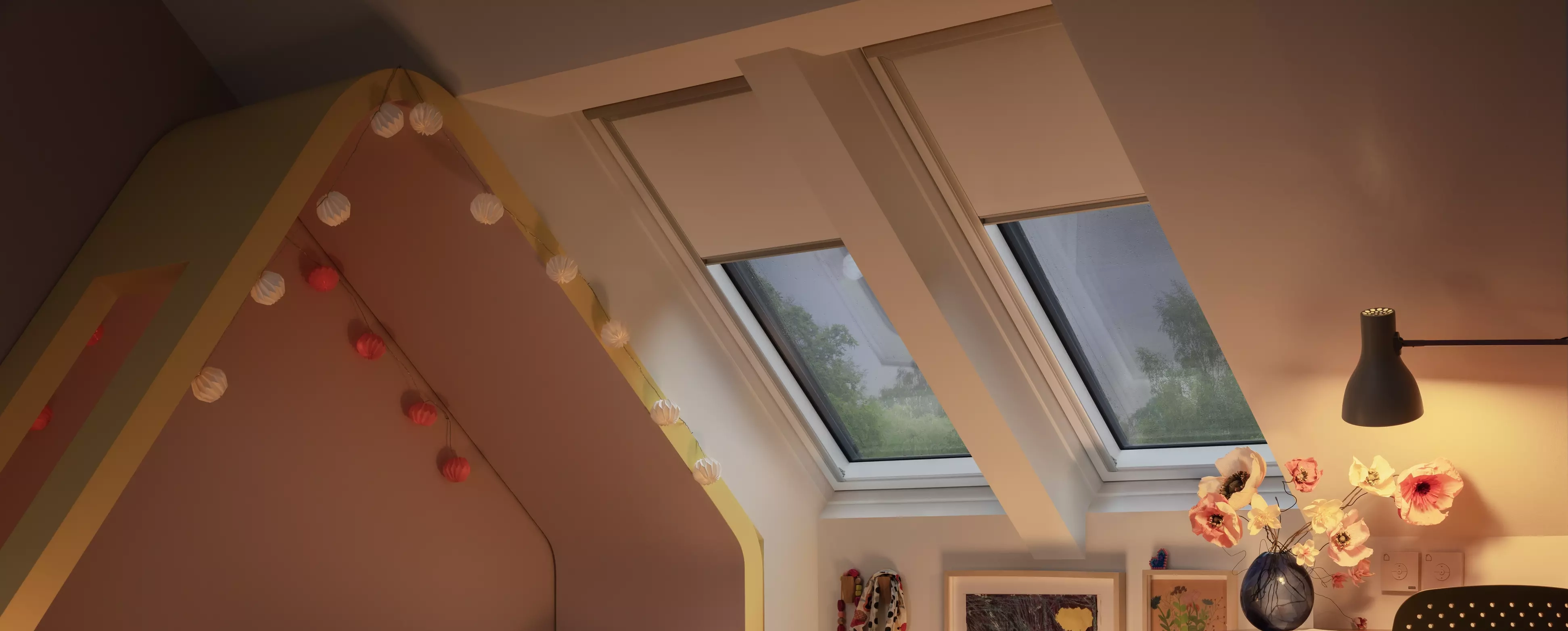 Attic kids room with sloped ceiling, VELUX roof windows, and playful decor.