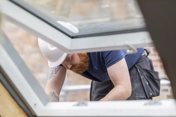 Ein Handwerker baut mit Handschuhen vorsichtig ein Dachfenster ein | VELUX Magazin