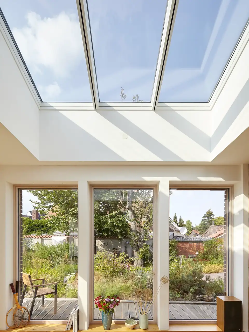 Salon avec grande baie vitrée donnant sur un jardin et fenêtres de toit VELUX 