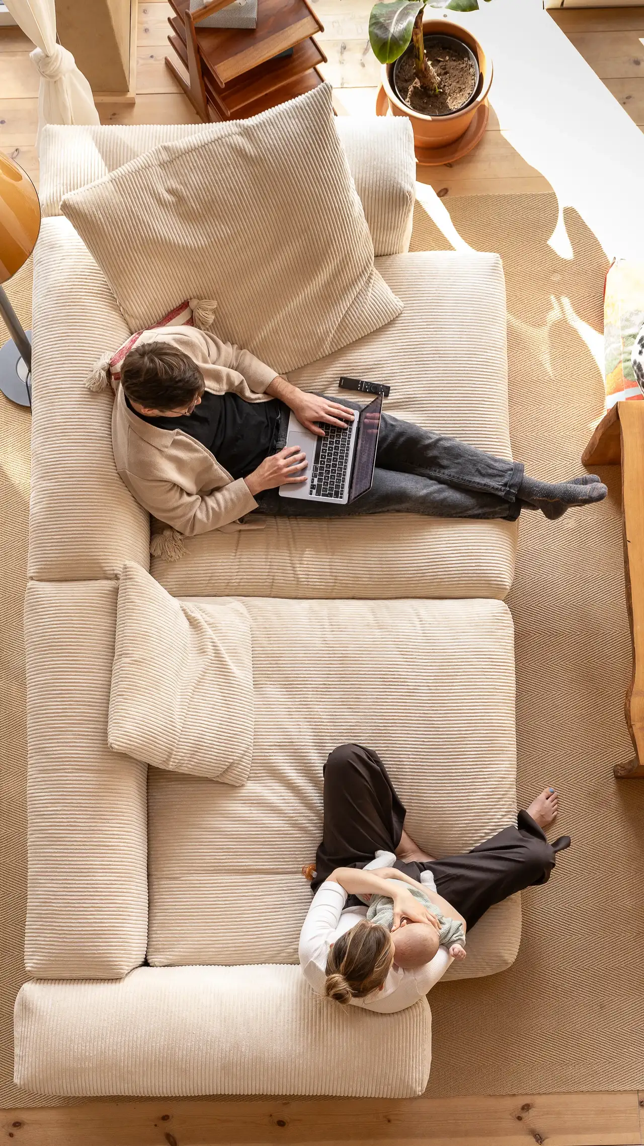 Ein Paar entspannt sich auf einem gemütlichen Sofa in einem sonnendurchfluteten Wohnzimmer und genießt das natürliche Licht durch VELUX Dachfenster. | VELUX Magazin