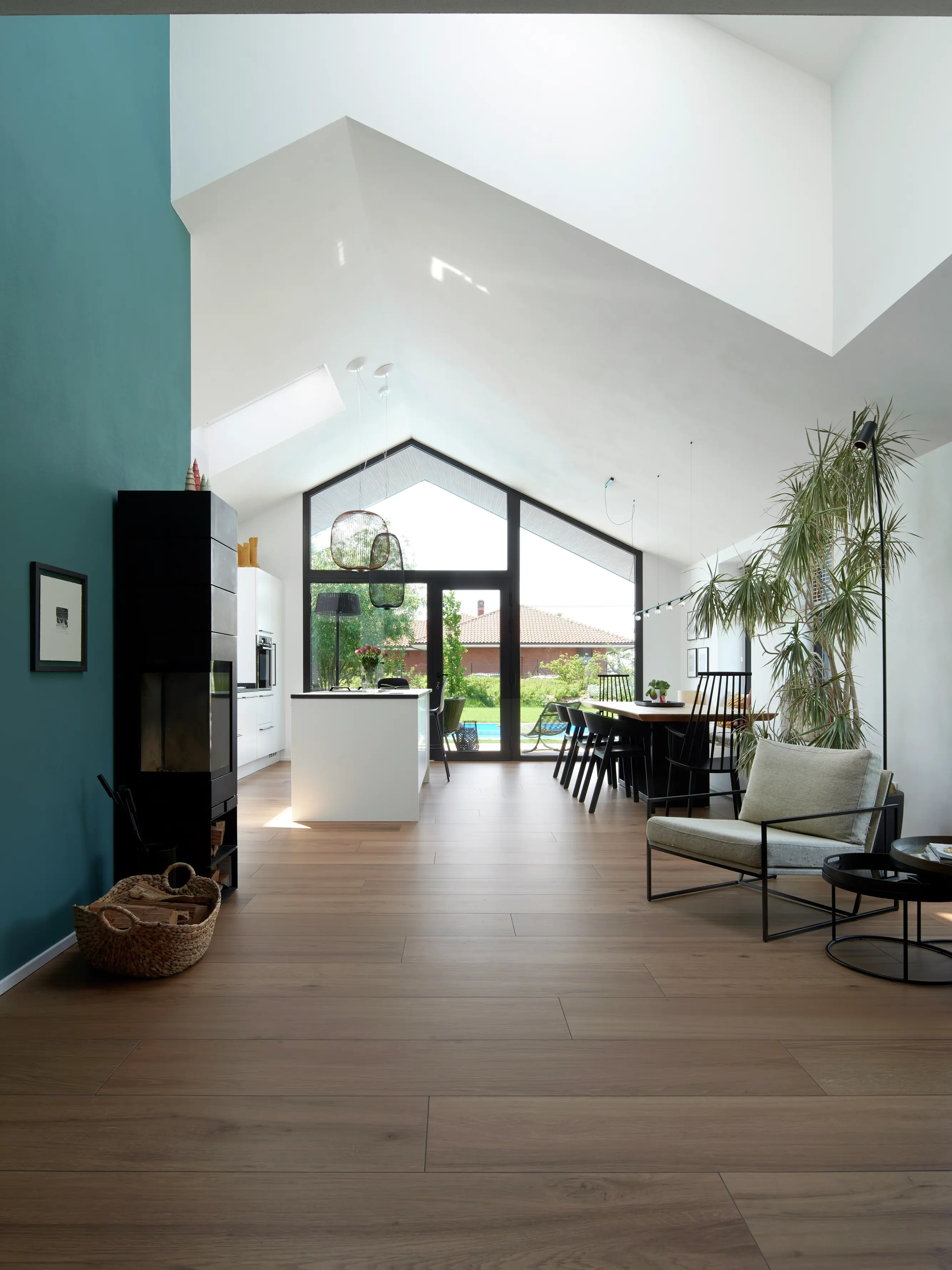 Soggiorno moderno con finestre per tetti VELUX, pavimenti in legno e vista sul giardino.