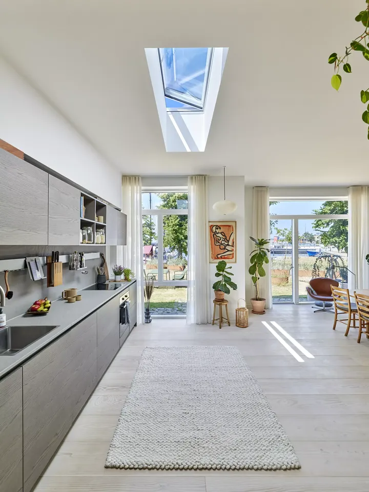 Moderne Küche mit VELUX Dachflächenfenster, grauen Schränken und einem weißen Teppich.