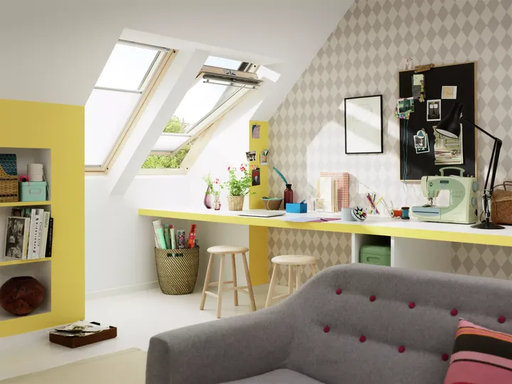 Dachboden-Bastelzimmer mit VELUX Dachflächenfenster, gelben Akzenten und einem organisierten Schreibtischbereich.