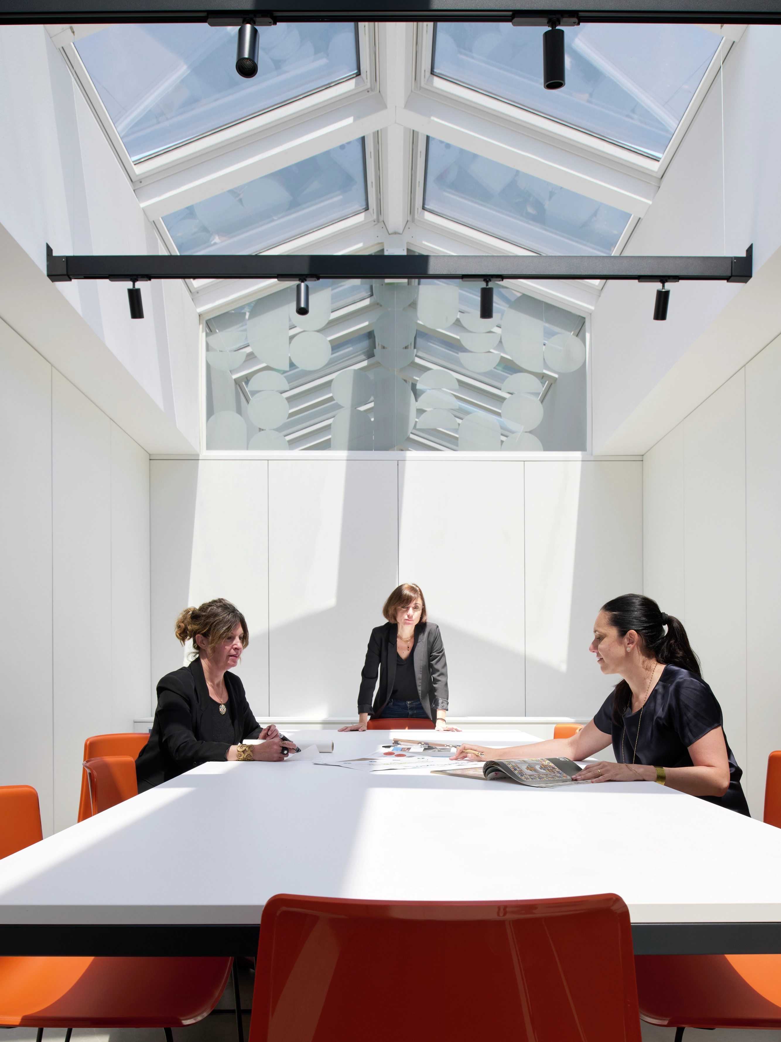 Tre donne intorno a un grande tavolo illuminato da finestre per tetti VELUX