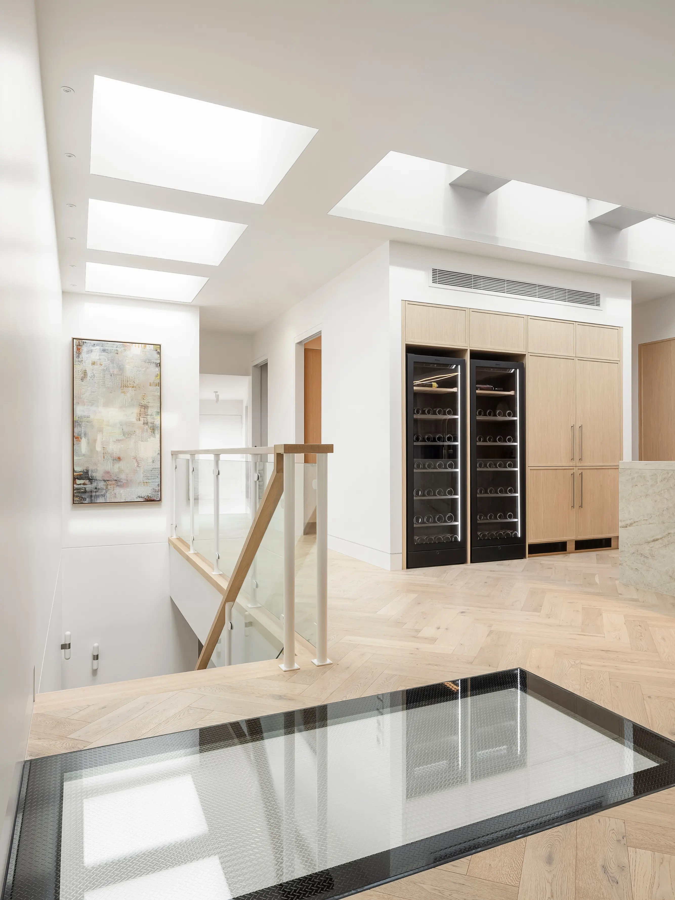 Modern upstairs hallway with VELUX flat roof windows and glass floor over stairwell.