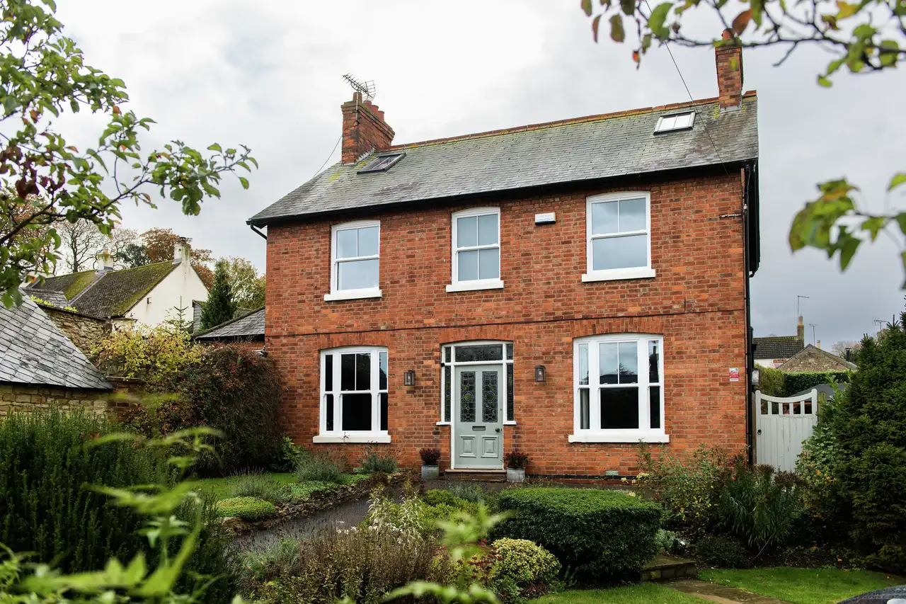 Brick house with slate roof and VELUX roof windows, surrounded by garden. 