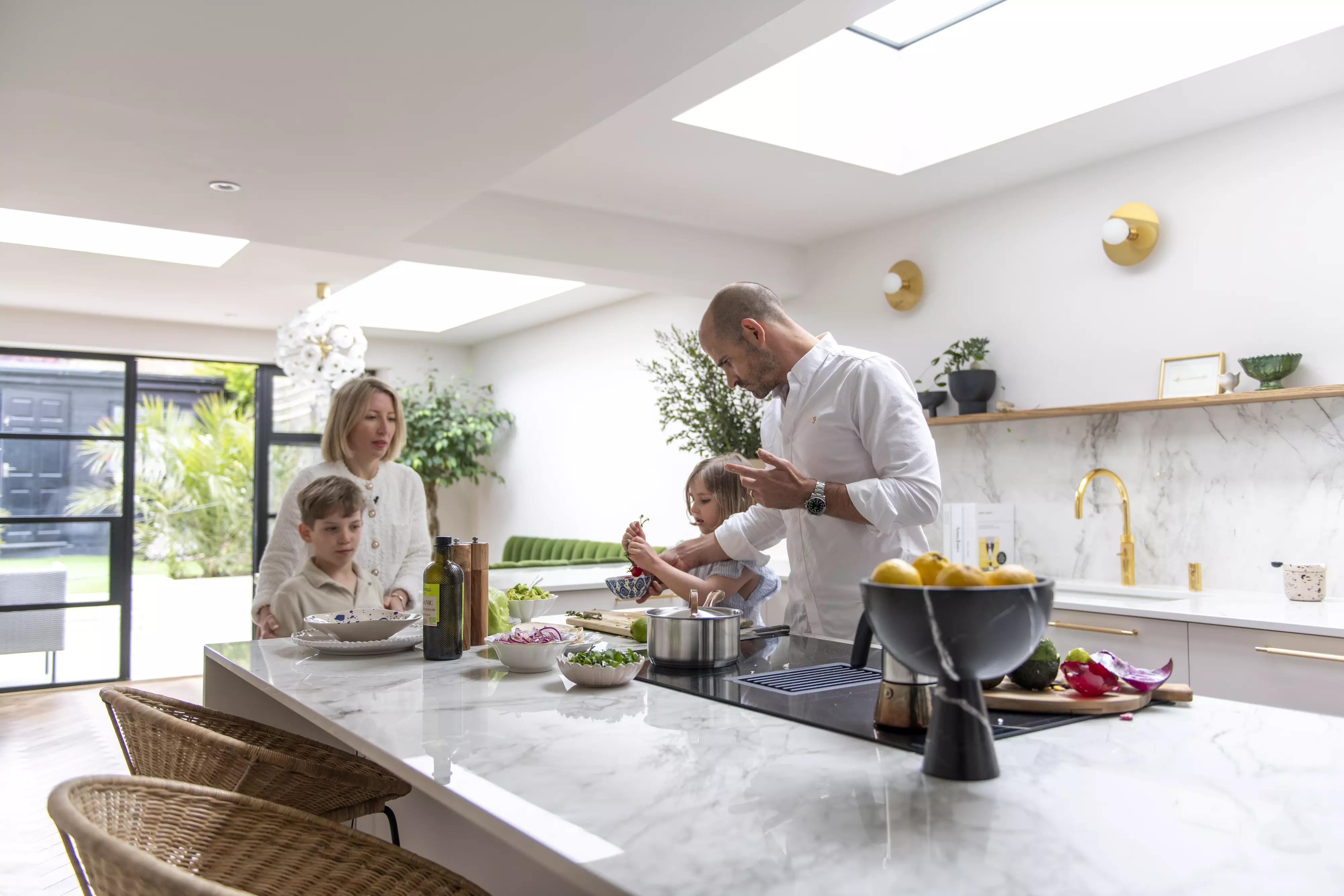 Modern kitchen with VELUX roof window, family cooking together, marble countertops.