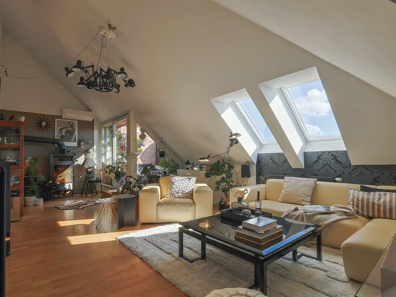 Divano angolare beige in un soggiorno luminoso con grandi lucernari e un balcone come fonti di luce naturale | VELUX Magazine