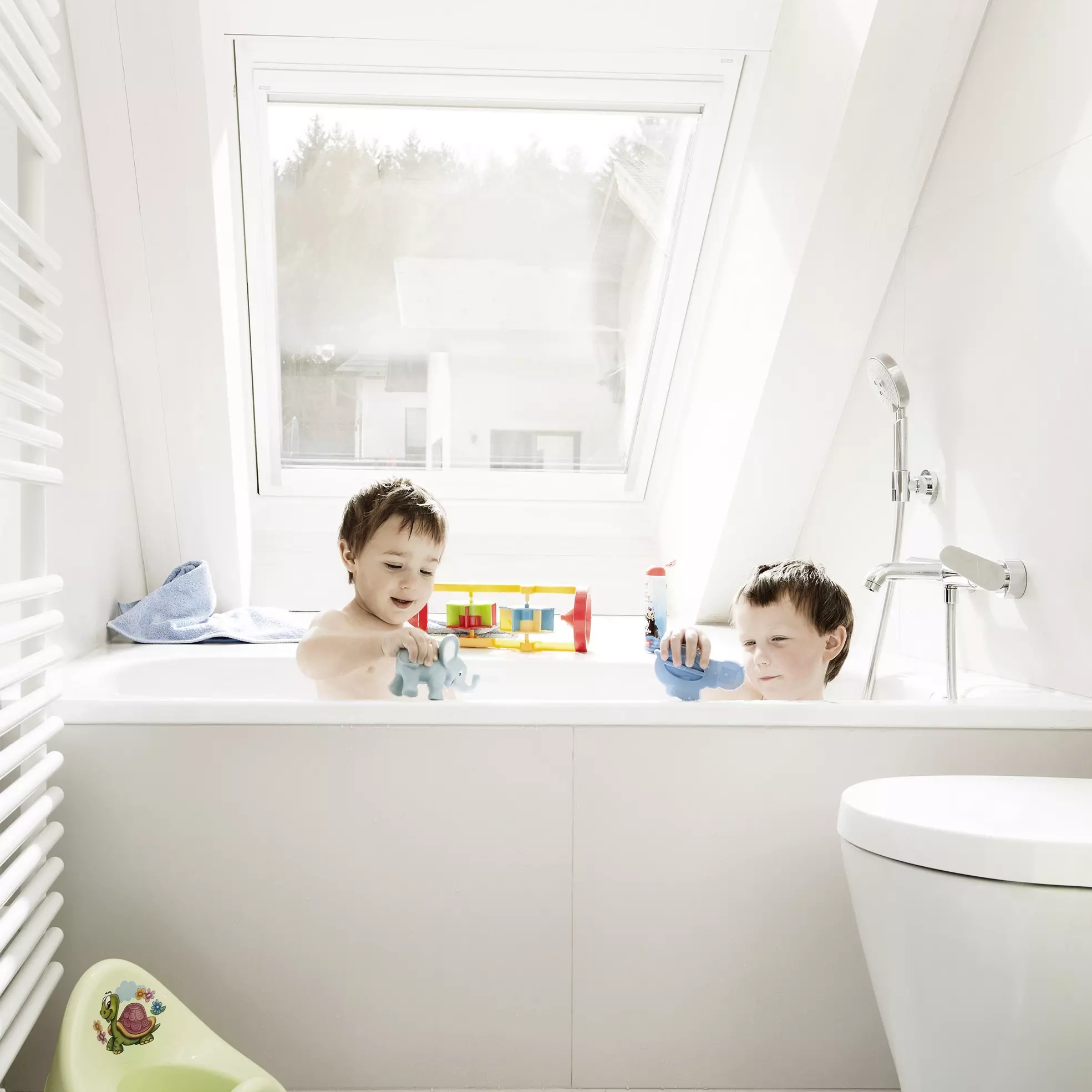 Bathroom with sloped ceiling and VELUX roof window, natural light entering.
