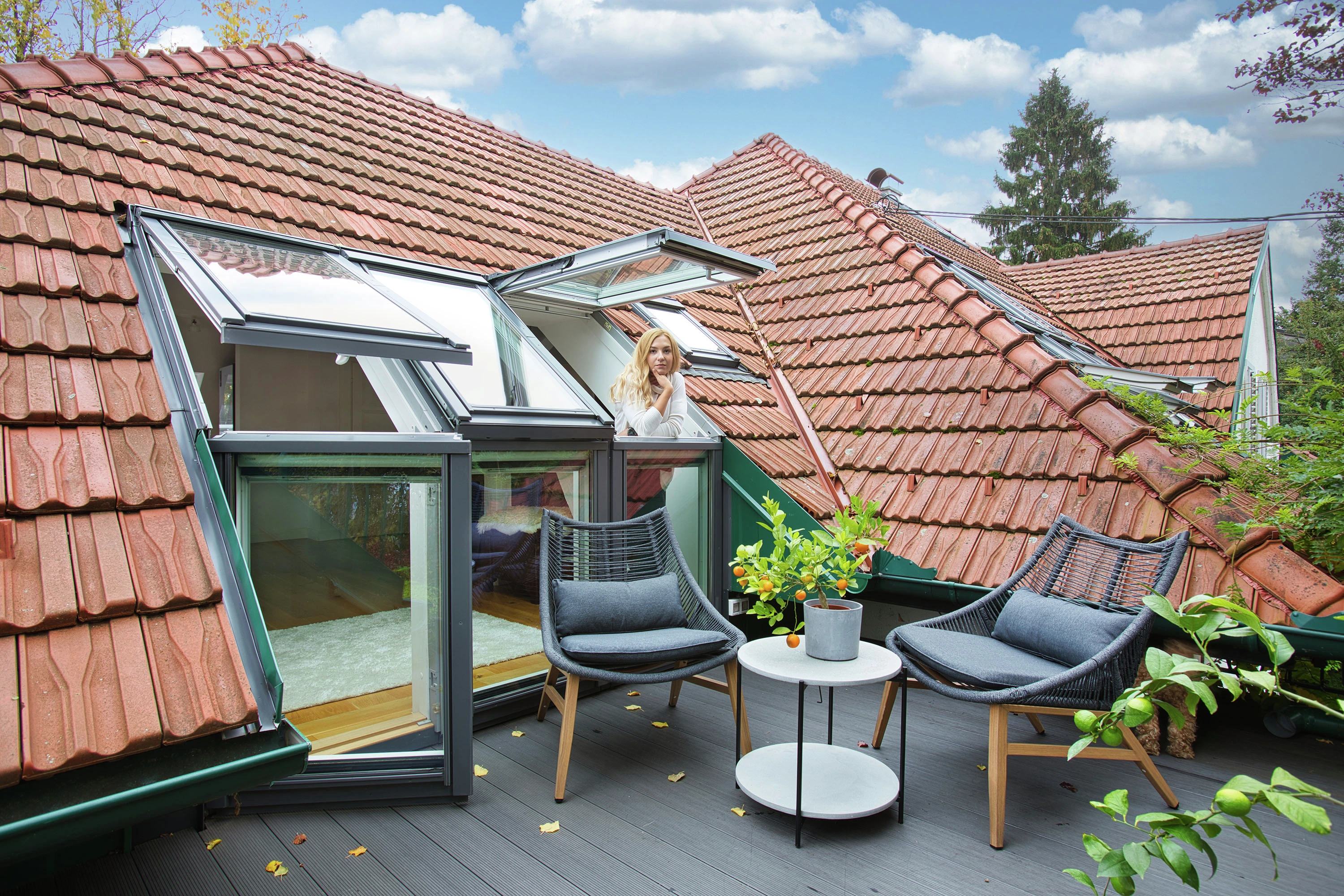 Jumta terase ar VELUX logiem, sēdvietu zonu un sarkanu dakstiņu jumtu.