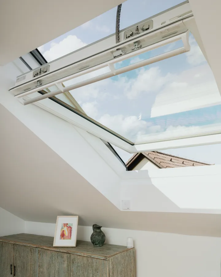 Detail otevřeného motorizovaného střešního okna VELUX s výhledem na oblohu | VELUX
