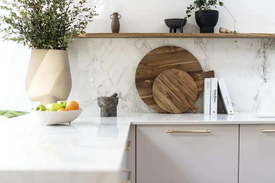 Piano cucina in marmo con taglieri in legno, cesto della frutta e piante