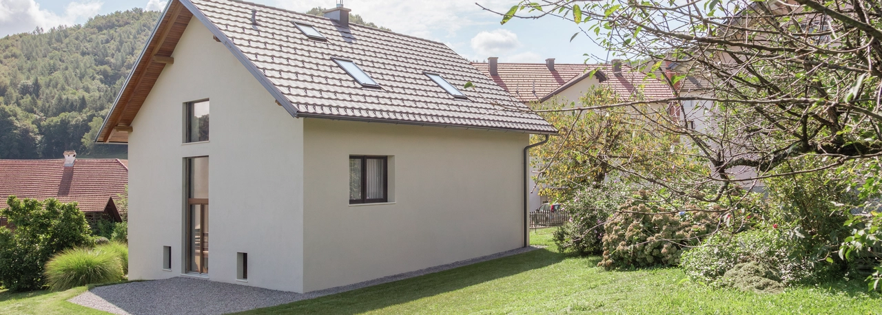 Zgrada s krovom okružena zelenim travnjakom.