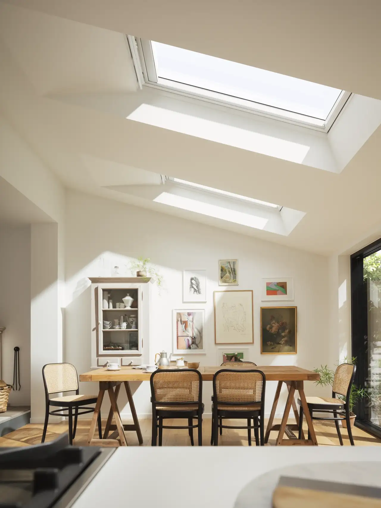 Sala da pranzo con soffitto spiovente e finestre da tetto che lasciano entrare abbondante luce naturale. 