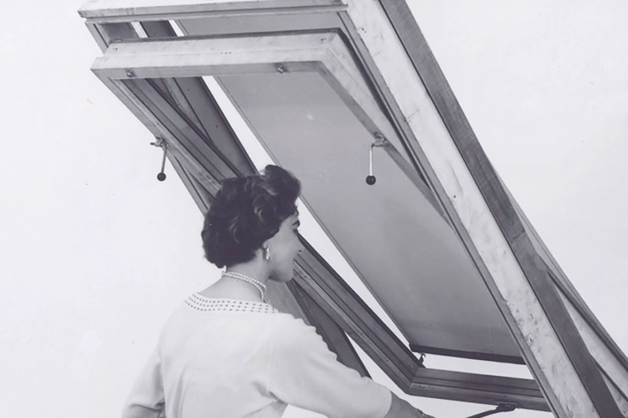 Vintage-Foto einer Person, die ein VELUX Dachflächenfenster öffnet, um Licht hereinzulassen.