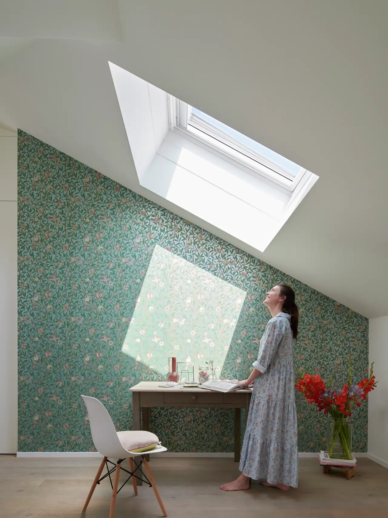 Bureau créatif en mansarde avec mur en briques blanches, bureau sur mesure et lumière naturelle par fenêtres de toit 