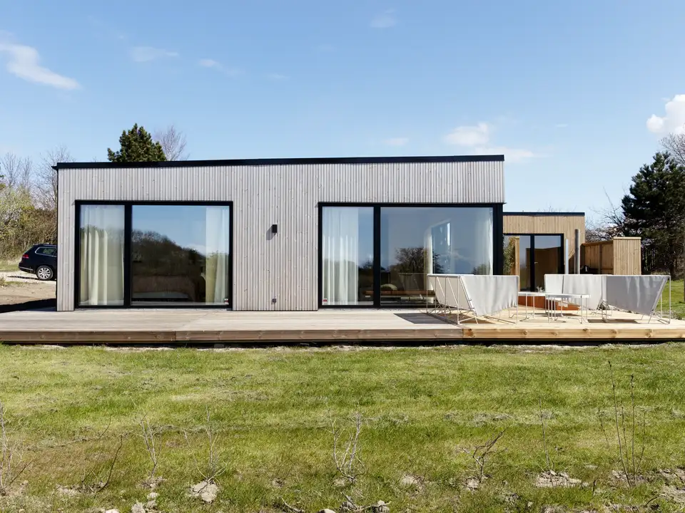Moderne sommerhus med fladt tag, stor træterrasse og tilbygning