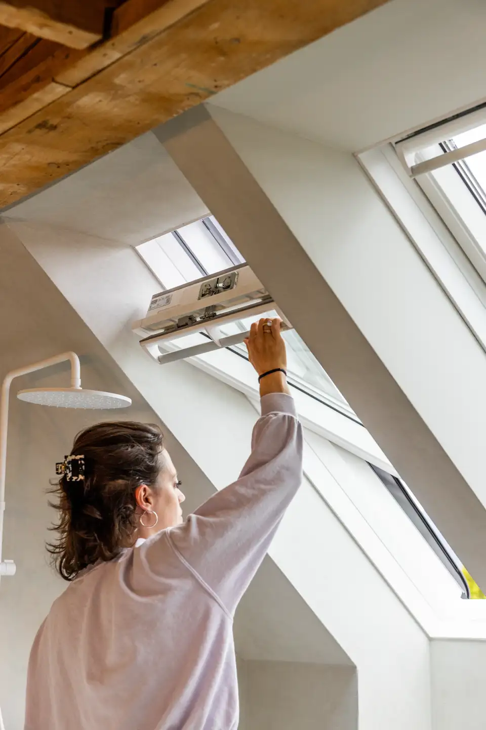 Donna apre finestra per tetti per facilitare la ventilazione e combattere l’aria secca.