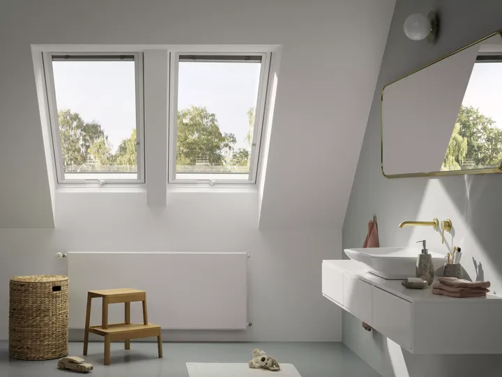 Modernes Badezimmer mit natürlichem Licht von VELUX Dachflächenfenstern, weißen Einrichtungsgegenständen und hölzernen Akzenten.