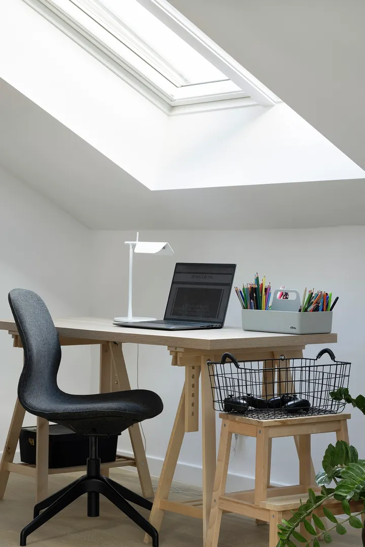  Minimalistički radni kutak u potkrovlju s krovnim prozorom, drvenim stolom i laptopom | VELUX