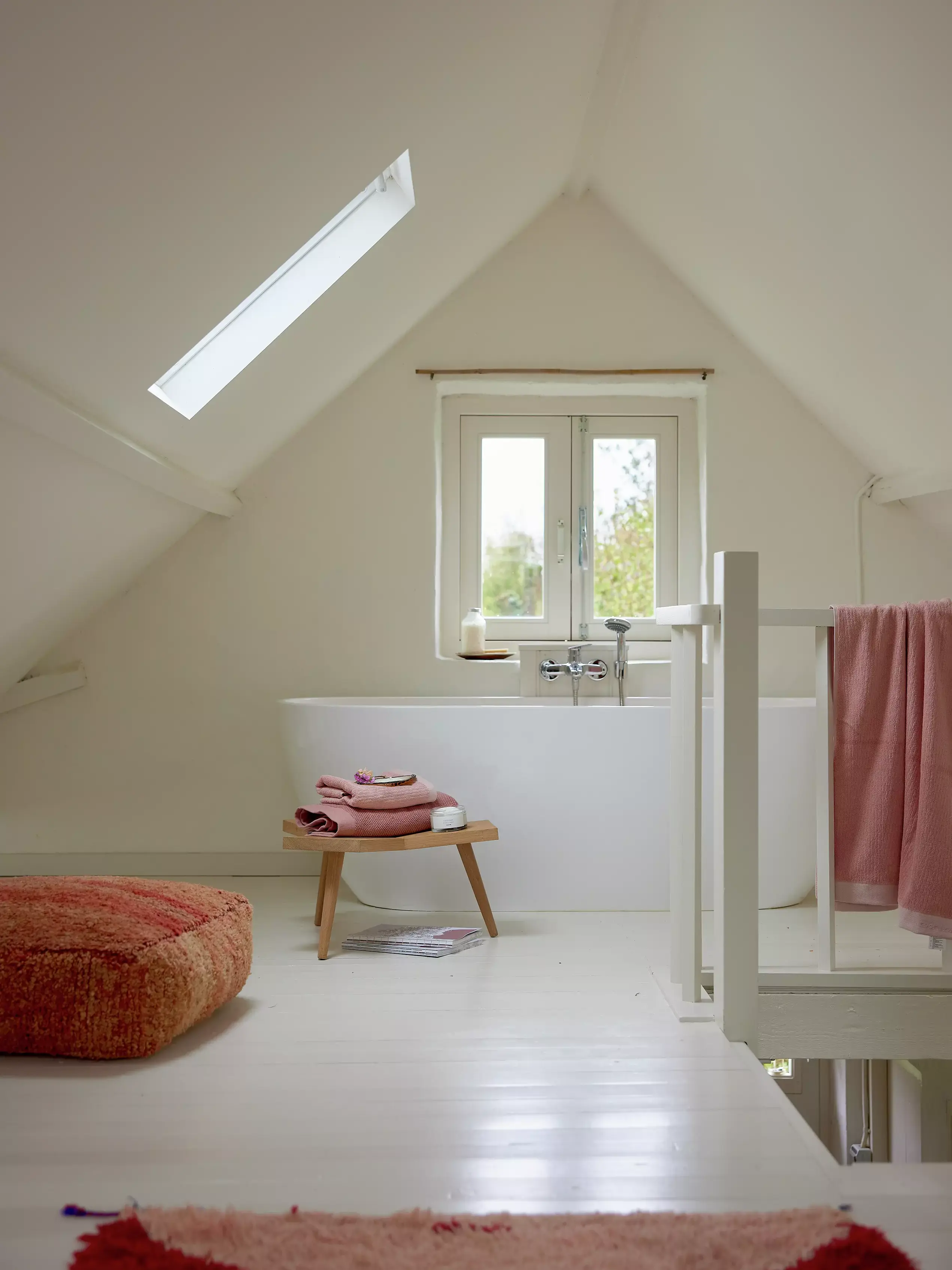 Salle de bain sous comble avec fenêtre de toit VELUX et décoration minimaliste.