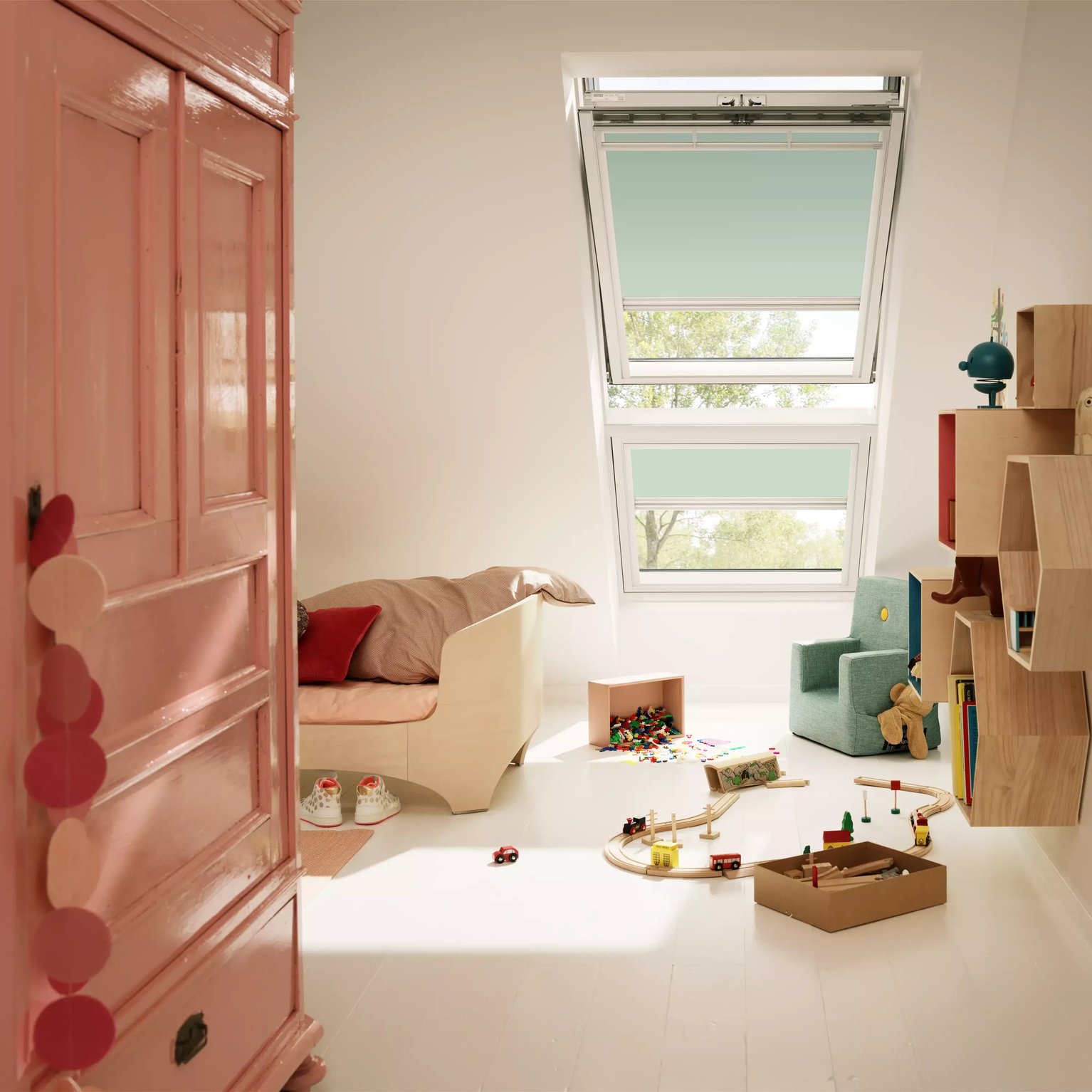 Attic kids room with sloped ceiling, VELUX roof window, toys, and pink wardrobe.