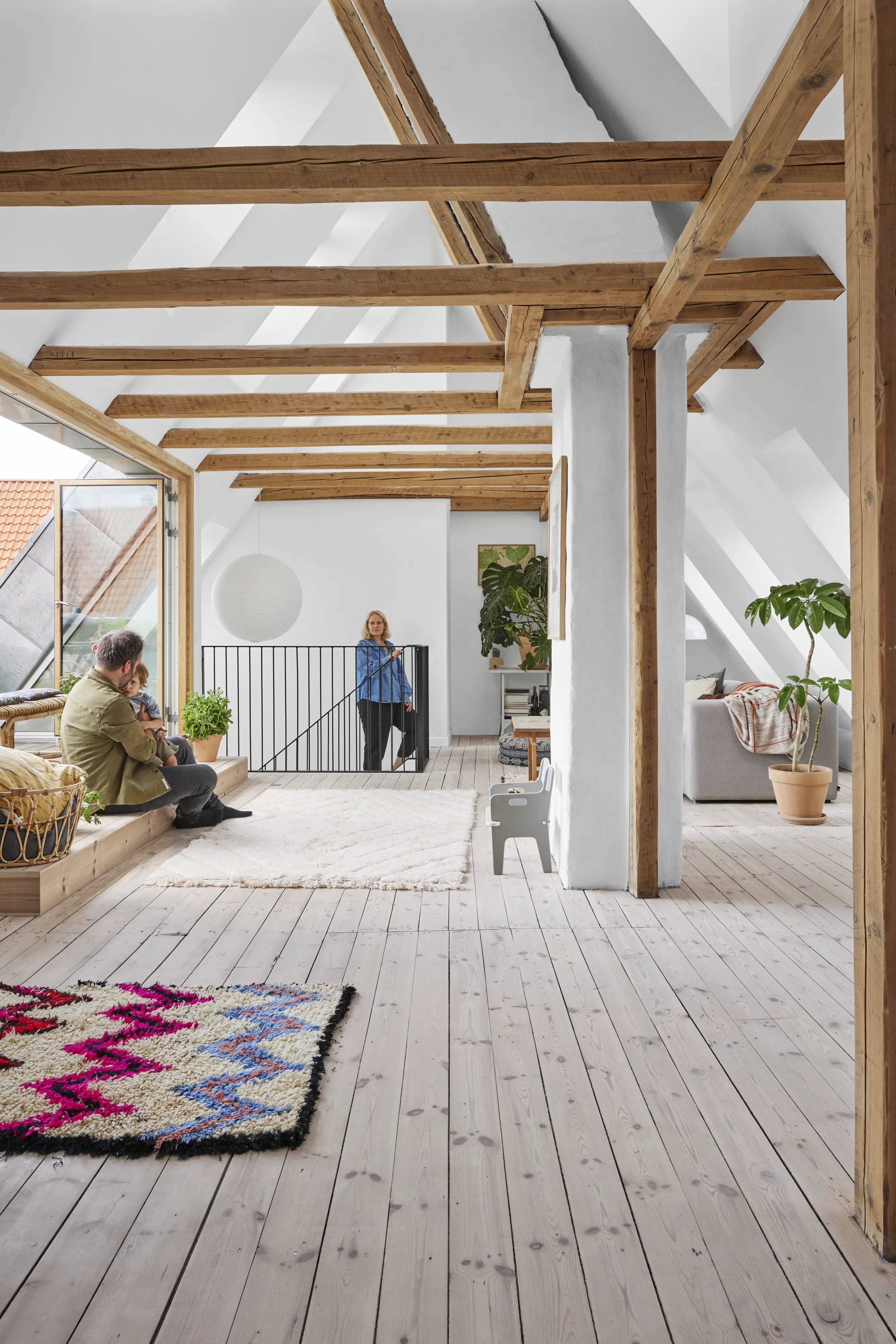 Plaši bēniņi ar koka sijām, ģimene atpūšas un jumta logiem. | VELUX