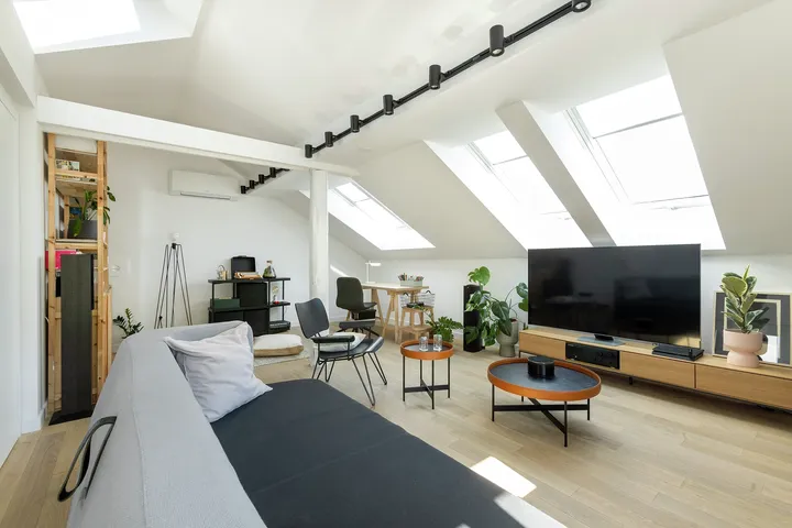 Svijetli dnevni boravak u potkrovlju s više krovnih prozora, modernim namještajem i drvenim podom | VELUX