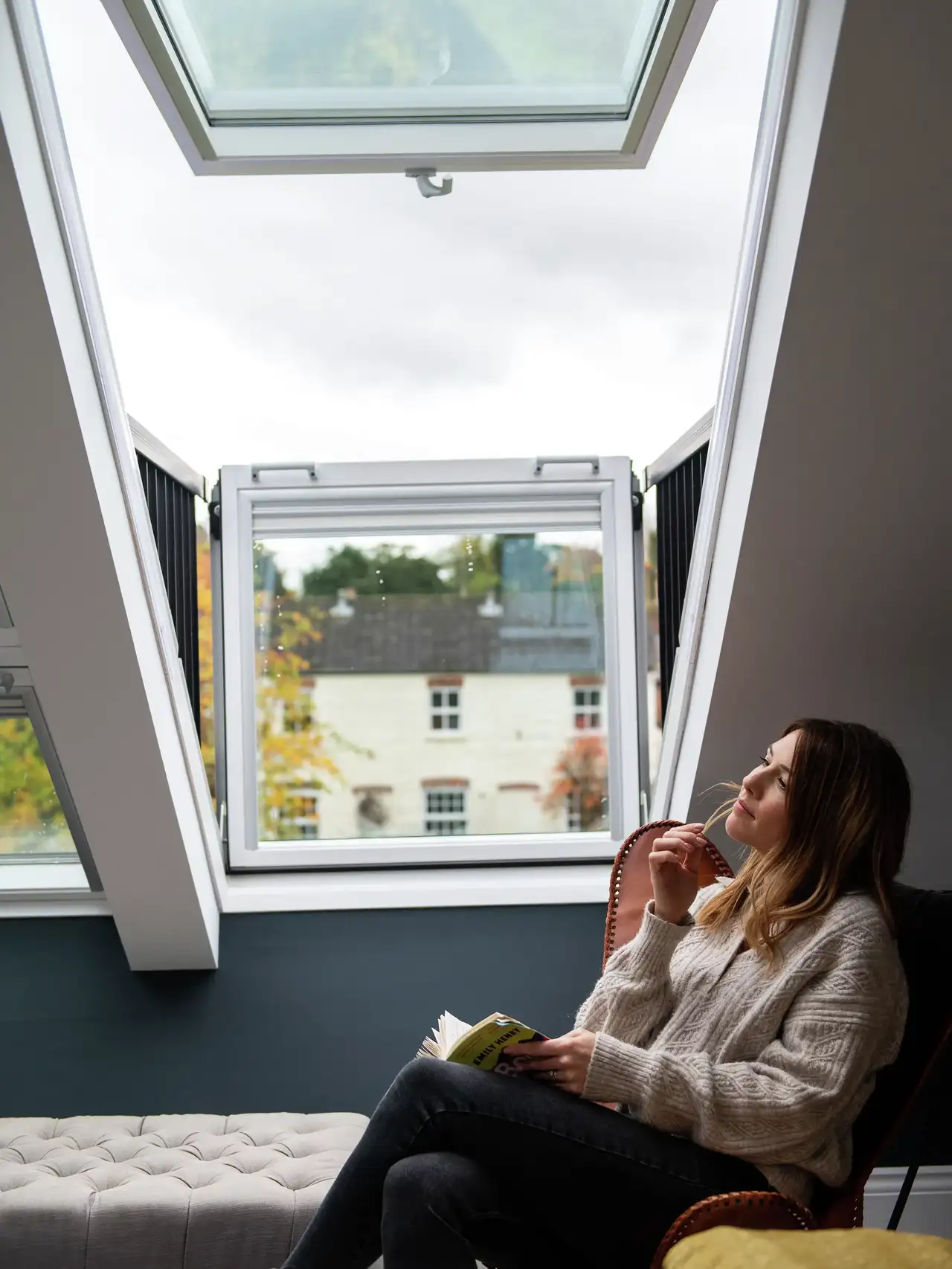 Attic room with open VELUX roof balcony, cosy reading area and ottoman. 