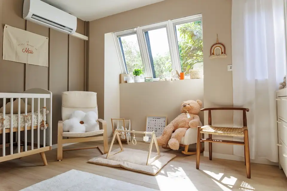 Un espace de jeu lumineux et confortable pour enfants avec trois fenêtres de toit VELUX, un grand ours en peluche, un portique de jeu et de petits objets décoratifs sur le rebord de la fenêtre.