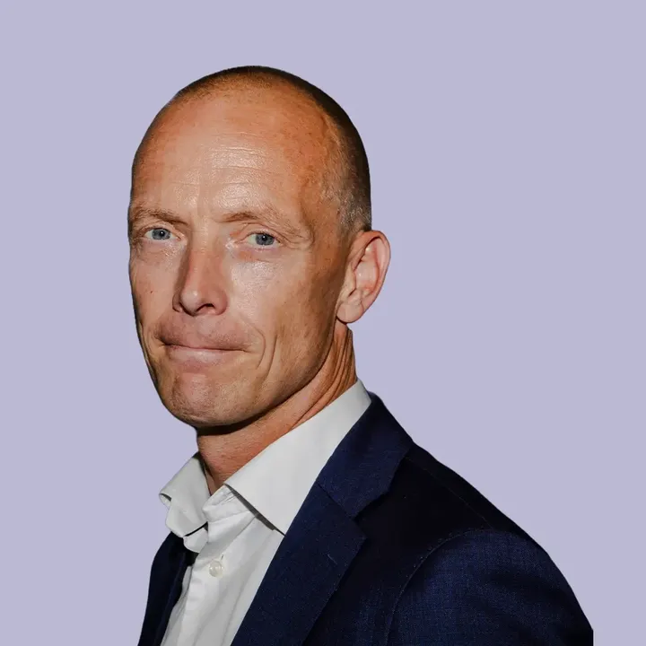 Man in navy blue suit and white shirt, professional appearance.