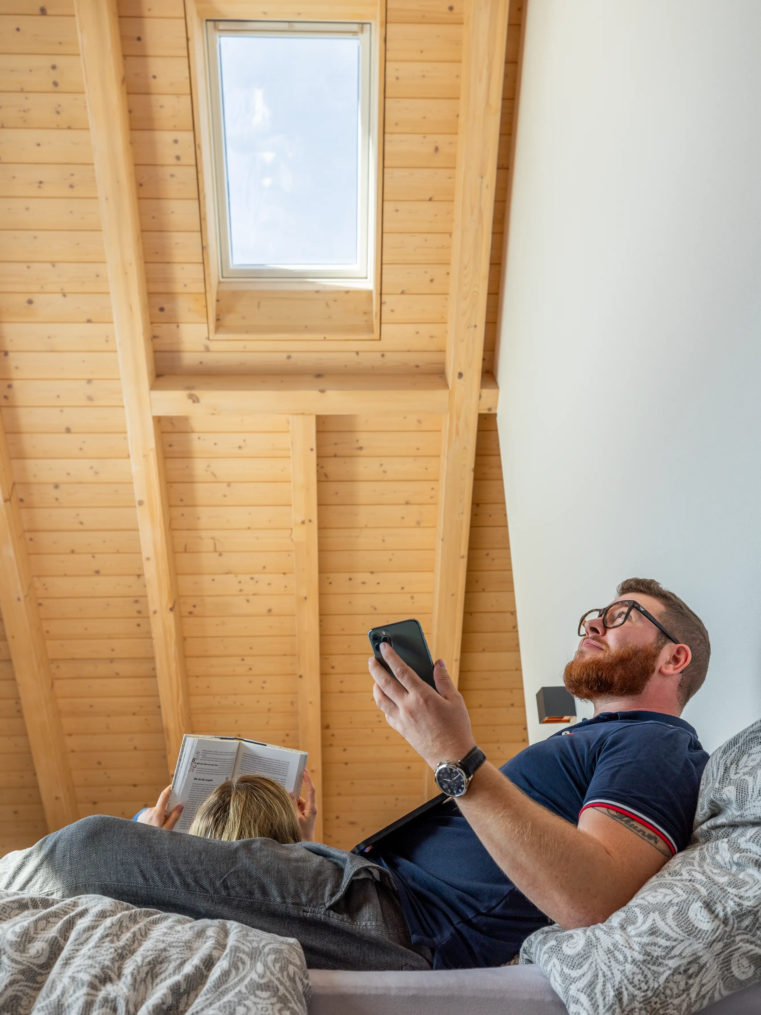 Un uomo controlla una finestra per tetti VELUX elettrica dal suo smartphone
