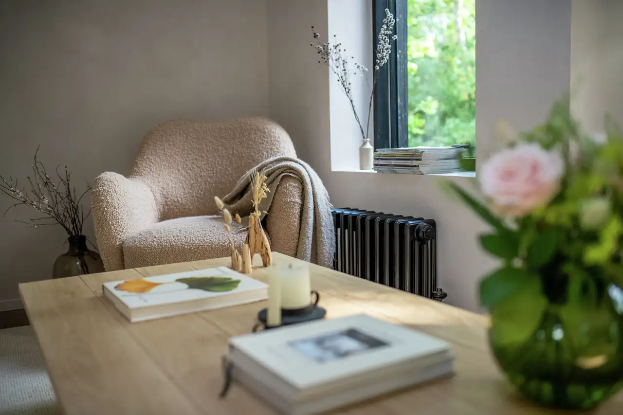 Holztisch mit Büchern und Blumenvase, dahinter Lesesessel | VELUX Magazin