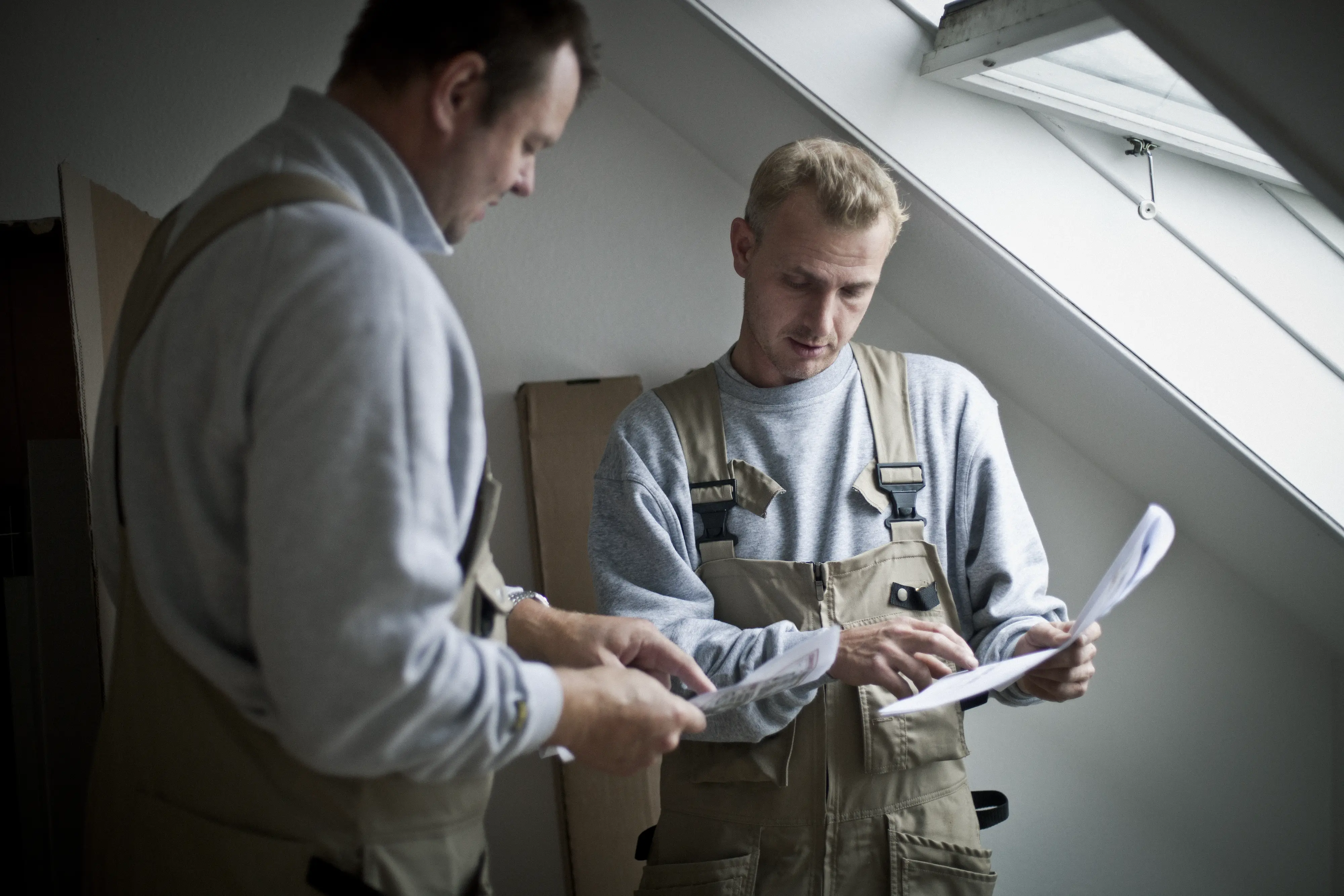 Munkások egy ferde mennyezetű, VELUX tetőablakos padlásszobában.
