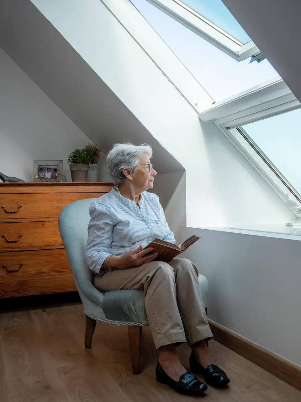 Sótão com teto inclinado e janela de telhado VELUX, com um acolhedor espaço de leitura. 