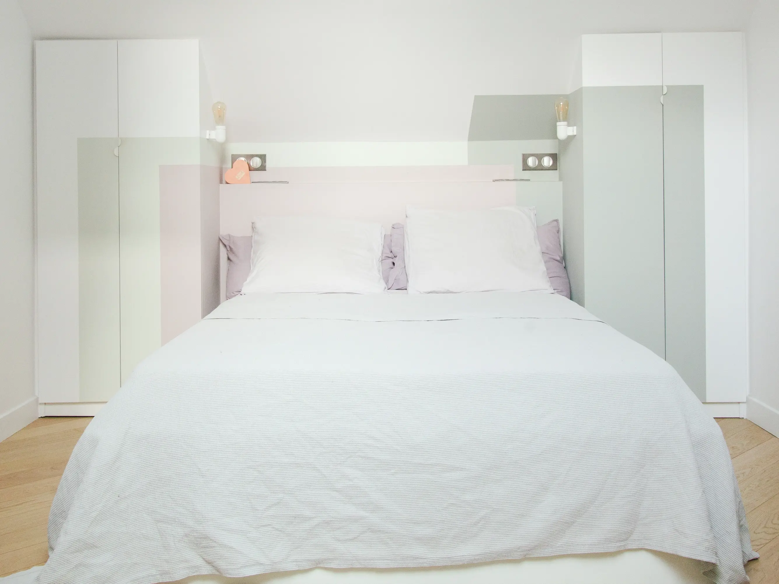 Chambre minimaliste moderne avec un grand lit et des armoires encastrées.