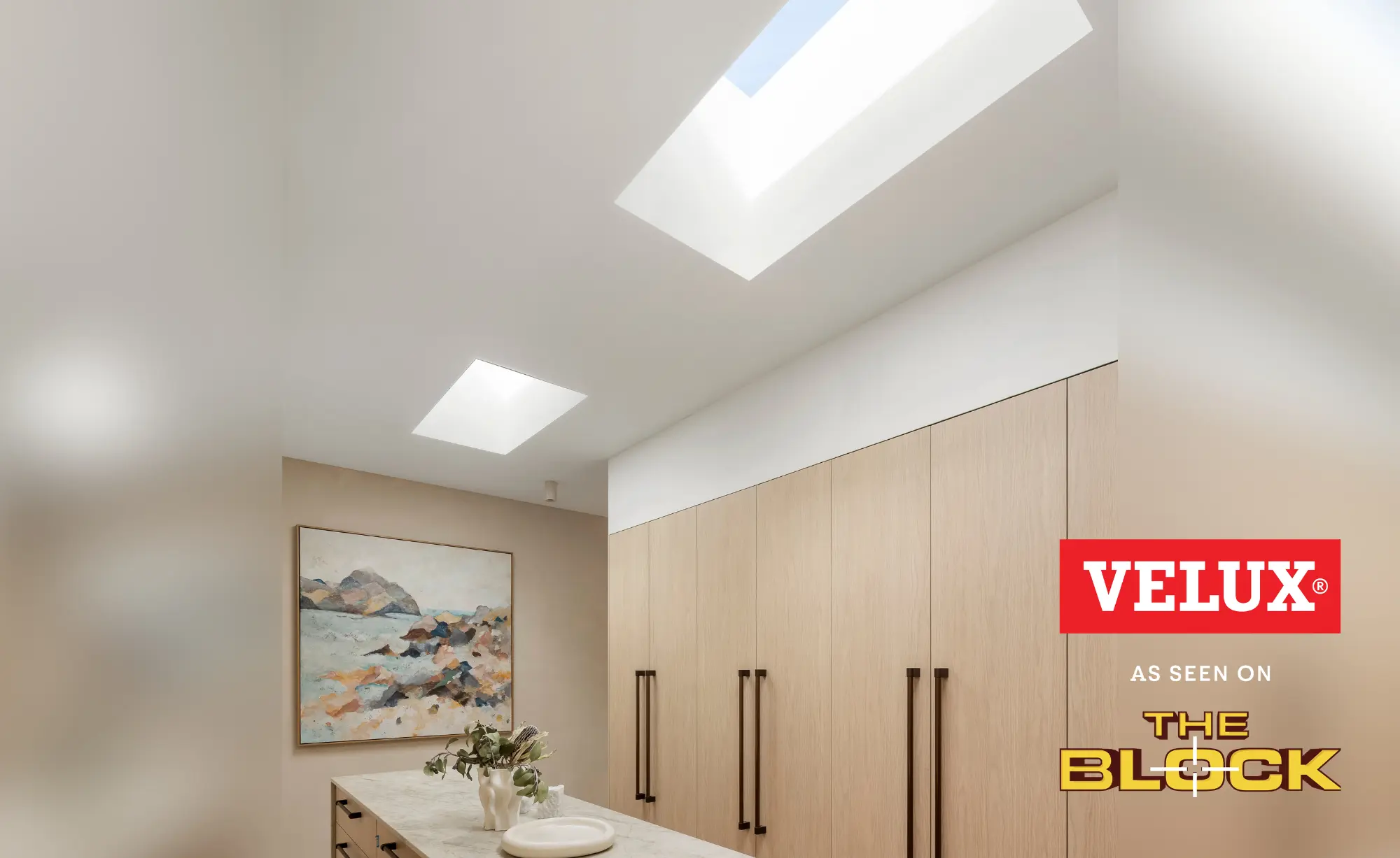 Modern hallway with VELUX flat roof window lighting pale wood cabinets and artwork.